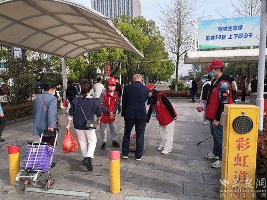 志愿服務(wù)隊(duì)在人民醫(yī)院路口開展文明交通體驗(yàn)活動(dòng)，并幫助老人提重物.jpg.jpg
